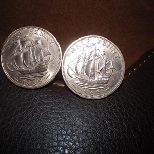 Può includere: Due monete britanniche da mezzo penny d'argento del 1965, raffiguranti una nave a vela e il testo "HALF PENNY" sul dritto.