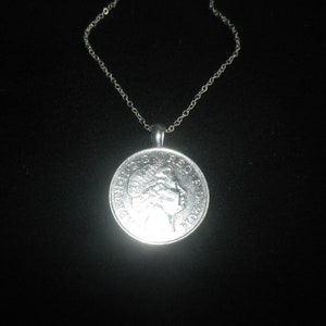 May include: A silver chain necklace with a silver coin pendant featuring a profile of a woman's face.