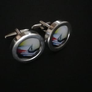 May include: A pair of silver cufflinks with a colourful abstract design inside each cufflink.