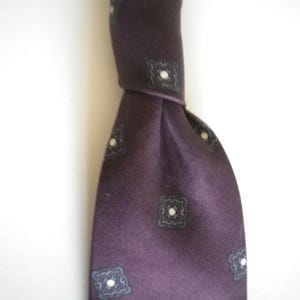 May include: A dark purple silk tie with a repeating pattern of white and gray squares.