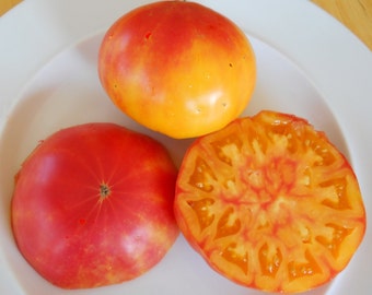 May include: Three tomatoes, one whole red tomato, one whole yellow tomato with red streaks, and one sliced yellow tomato with red streaks.