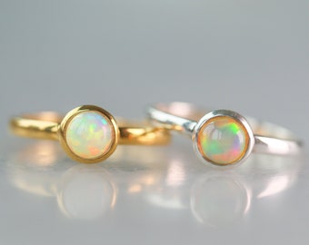 May include: Two simple rings with opal gemstones. One ring is gold and the other is silver.