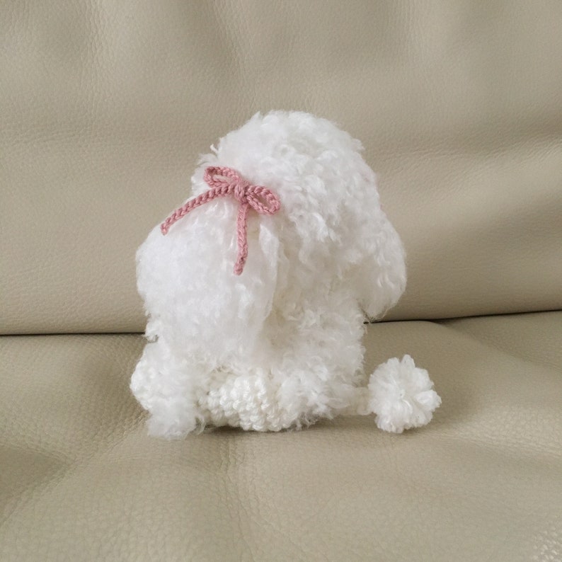 Peut inclure: Un jouet en crochet en forme de caniche blanc avec un n&oelig;ud rose. Le jouet a une texture moelleuse et une queue en pompon.