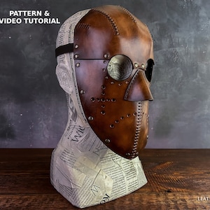 May include: A brown leather mask with a nose guard and eye holes. The mask has a stitched design and metal rivets. The mask is on a mannequin head.