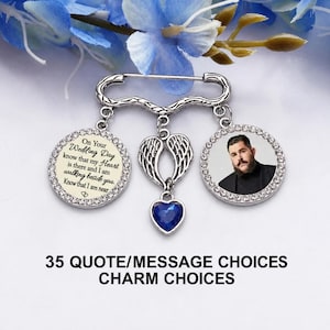 May include: A silver-toned brooch pin featuring two circular pendants framed with clear crystals. One pendant displays the text On Your Wedding Day know that my Heart is there and I am walking beside you. Know that I am near. The other shows a man's portrait. A central silver angel wing charm hangs with a blue heart-shaped stone.