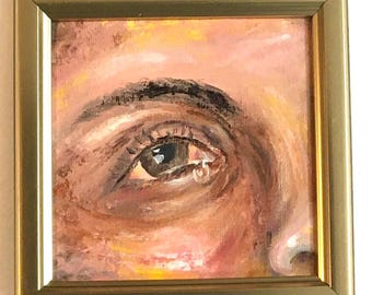 Puede incluir: Pintura al óleo enmarcada de un ojo humano, con una lágrima. La obra presenta una vista de cerca del ojo, con pinceladas detalladas y una paleta de colores cálidos de marrones, rosas y amarillos. El marco es dorado.