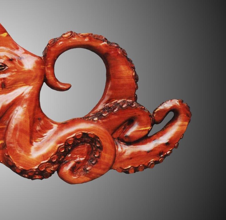 Puede incluir: Primer plano de una escultura de madera de un pulpo con tent&aacute;culos detallados. La escultura est&aacute; tallada en madera de color marr&oacute;n rojizo y tiene un aspecto natural y org&aacute;nico.