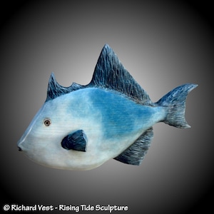 May include: A blue and white wooden sculpture of a fish. The fish has a large, round body and a small, pointed head. The sculpture is carved with intricate details, including scales and fins.
