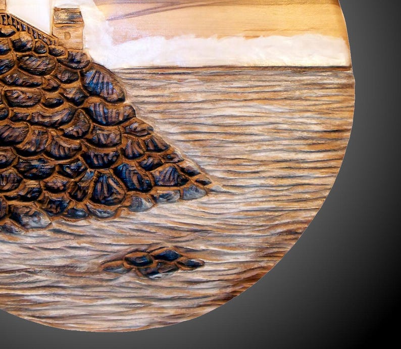 A round wall carving depicting an East coast lighthouse.  White staining on the lighthouse and waves and also for the fog.  hanger on back, ready for wall  hanging.  signed/copyrighted, for indoor display only. Carved in red gum wood.