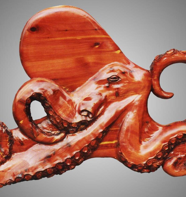 Puede incluir: Una escultura de madera de un pulpo de color marr&oacute;n rojizo. El pulpo est&aacute; tallado con detalle, con sus tent&aacute;culos y ojos claramente visibles.
