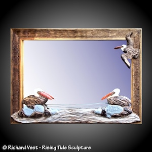 May include: A wooden mirror with a carved pelican scene. Two pelicans are perched on rocks in the water, while a third pelican flies overhead. The mirror is framed in a rustic wood frame.