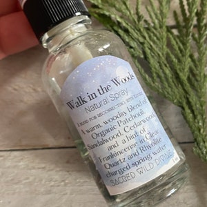 以下が含まれることがあります： 黒いスプレーキャップと「Walk in the Woods Natural Spray A blend for reconnecting with nature A warm, woodsy blend of Organic Patchouli, Sandalwood, Cedarwood, and a hint of Frankincense in Clear Quartz and Rhyolite charged spring water SACRED WILD DIVINE 1 oz」と書かれたラベルが付いた透明なガラス瓶。