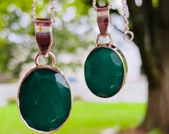 May include: Three silver necklaces with oval-shaped green gemstone pendants. The pendants are of different sizes.