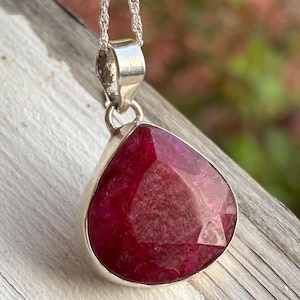 May include: A teardrop-shaped pendant with a deep red ruby gemstone set in sterling silver.