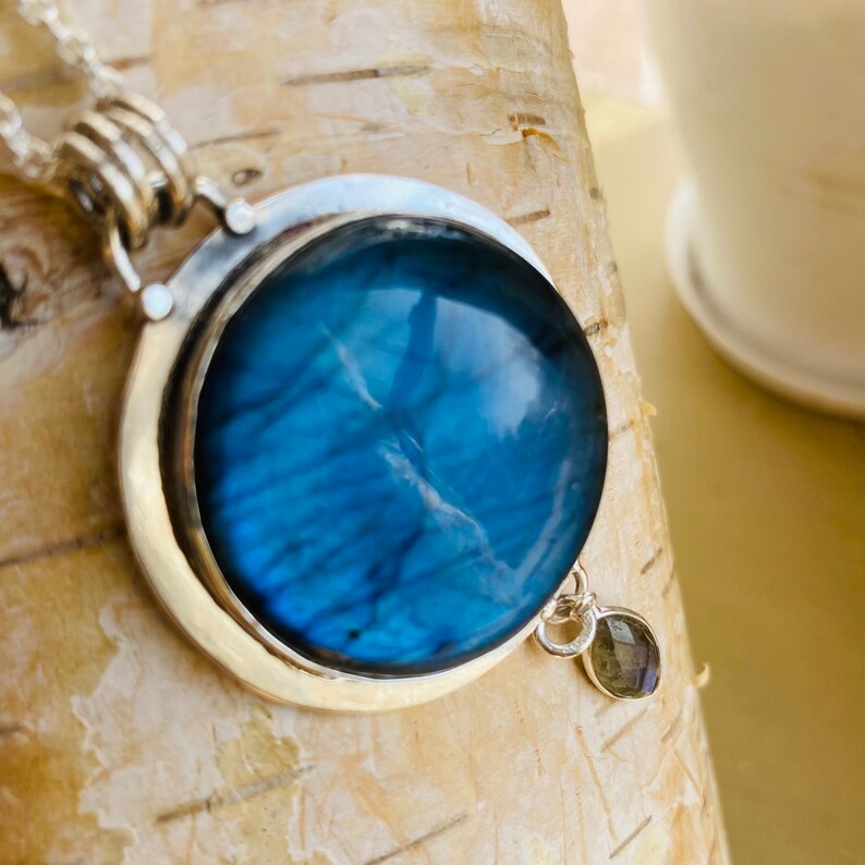 "Elevate your style with Earthkarmajewellery's Sterling Silver Labradorite Pendant, evoking the enchanting allure of a round blue moon, skillfully set in sterling silver for distinctive elegance, featuring a moonstone dangle."