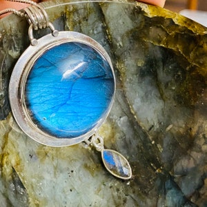 "Discover our Earth Karma Labradorite Pendant Necklace with a large round design, set in sterling silver and reminiscent of a cosmic galaxy, complemented with a moonstone dangle."