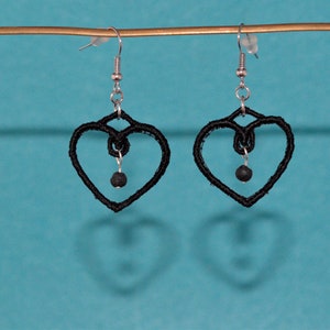 May include: A pair of black heart-shaped earrings with a small black bead hanging from each heart.