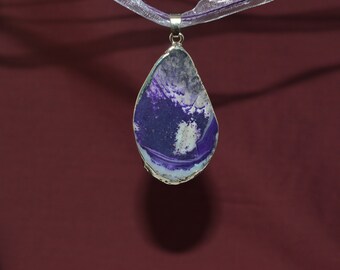 May include: A silver pendant with a teardrop-shaped purple and white agate stone. The stone has a swirling pattern and is set in a silver frame.