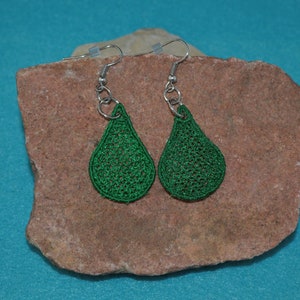 May include: A pair of green teardrop-shaped earrings with a delicate crocheted design. The earrings are made of a lightweight material and hang from silver hooks.