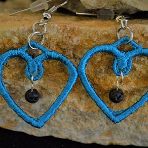 May include: A pair of turquoise blue heart-shaped earrings with black lava rock beads hanging from the bottom.