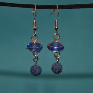 Könnte beinhalten: Ein Paar silberne Ohrringe mit blauen Glasperlen und schwarzen Lavasteinen.