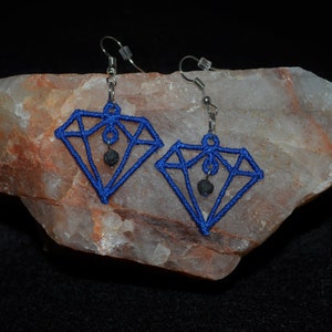 以下が含まれることがあります： 黒い溶岩ビーズが下からぶら下がった、青いダイヤモンド型のイヤリングのペアです。