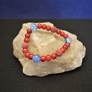 Può includere: Un braccialetto di perline rosse e blu con piccole perline rotonde. Il braccialetto è realizzato con perline di lava rossa e perline di vetro blu.