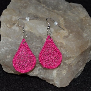 May include: A pair of pink teardrop-shaped earrings with a delicate crocheted design. The earrings are made with silver hooks.
