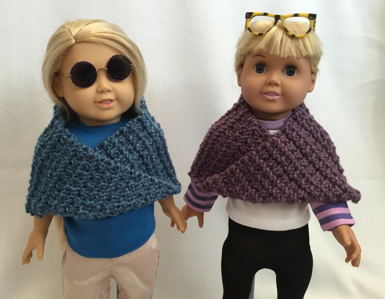 Puede incluir: Dos mu&ntilde;ecas con bufandas de punto. La mu&ntilde;eca de la izquierda lleva una bufanda azul y gafas redondas. La mu&ntilde;eca de la derecha lleva una bufanda morada y gafas de montura amarilla.