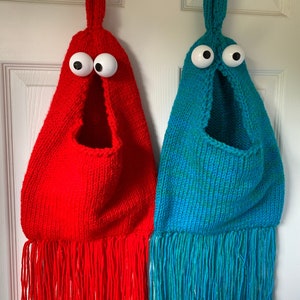 May include: Two knitted hanging pockets with googly eyes and fringe. One is red and the other is blue.
