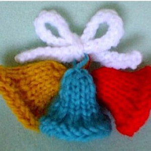 May include: Four knitted bells with a white bow. The bells are yellow, blue, red, and white.
