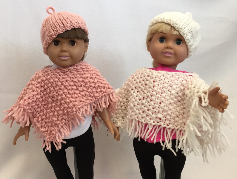 Puede incluir: Dos mu&ntilde;ecas con ponchos y gorros tejidos. La mu&ntilde;eca de la izquierda lleva un poncho y un gorro rosa, mientras que la mu&ntilde;eca de la derecha lleva un poncho y un gorro blanco.