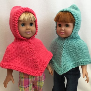 Puede incluir: Dos mu&ntilde;ecas con ponchos de punto con capucha. Una mu&ntilde;eca lleva un poncho rosa y la otra un poncho turquesa.
