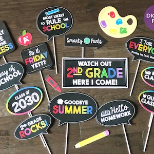 May include: A set of 12 printable photo booth props for a second grade graduation party. The props feature colorful speech bubbles with phrases like "Watch Out 2nd Grade Here I Come!" and "2nd Grade Rocks!"