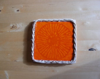 orange starburst tile trivet in wicker