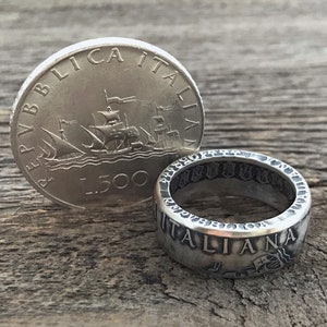 May include: A silver coin ring made from an Italian 500 Lire coin. The ring features the inscription "REPUBLICA ITALIANA" and a ship design. The coin is also shown next to the ring.