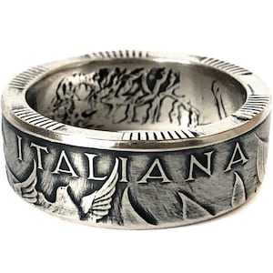 Pode incluir: Um anel de prata feito com uma moeda italiana. O anel apresenta a inscrição "ITALIANA" e um desenho de dois pássaros em voo.