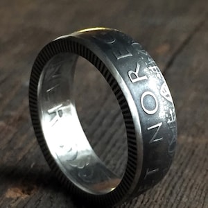 以下が含まれることがあります： 「NORWAY」と刻まれたコインで作られた銀の指輪です。