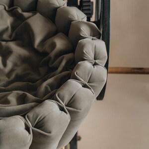 Puede incluir: Un coj&iacute;n redondo y capiton&eacute; de color gris claro, con una textura suave y aterciopelada. El coj&iacute;n est&aacute; hecho de botones individuales redondos que se cosen juntos para crear un dise&ntilde;o &uacute;nico y c&oacute;modo.