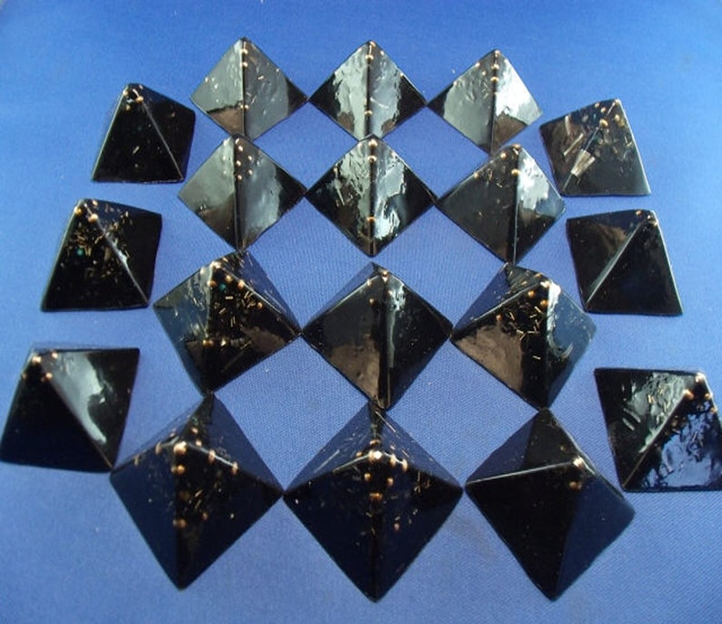 May include: A set of 16 black pyramid-shaped objects with gold accents. The pyramids are arranged in a grid pattern on a blue surface.