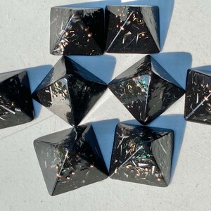 May include: Eight black pyramid-shaped crystal points with gold and green glitter embedded in the resin.