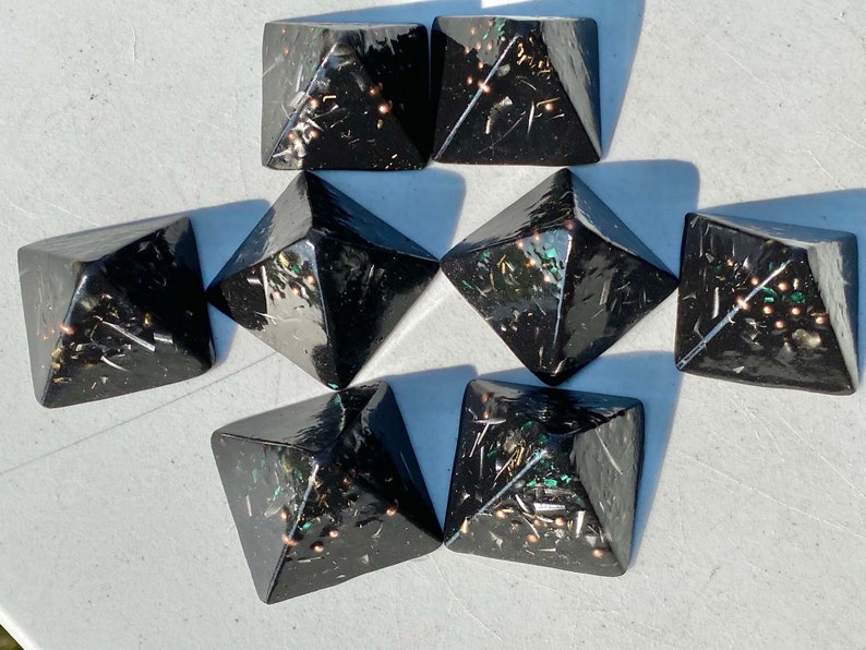 May include: Eight black pyramid-shaped crystal points with gold and green glitter embedded in the resin.