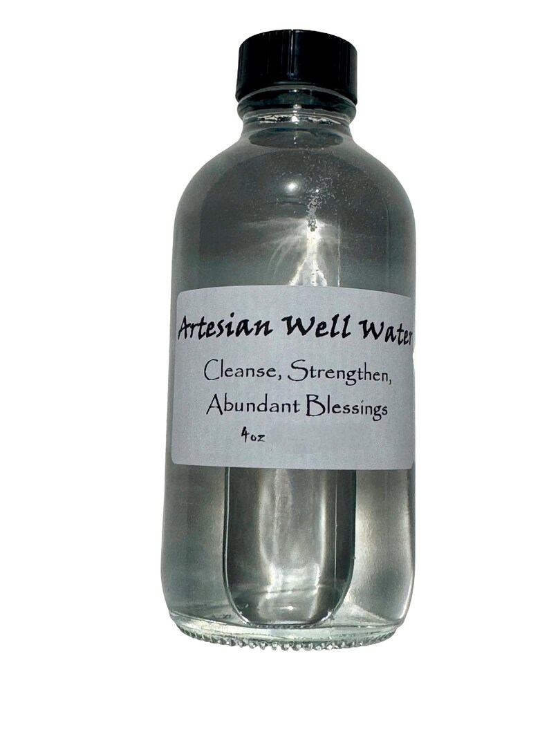 May include: A clear glass bottle with a black cap, filled with a liquid. A white label on the bottle reads "Artesian Well Water, Cleanse, Strengthen, Abundant Blessings, 4 oz."