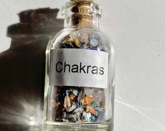 May include: A small glass bottle with a cork stopper filled with colorful crystals and a white label that reads "Chakras".