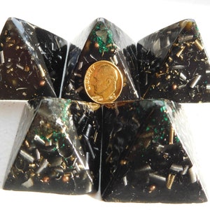 May include: Five black pyramids with gold and green flecks, arranged in a star shape. A US penny is placed in the center of the star.