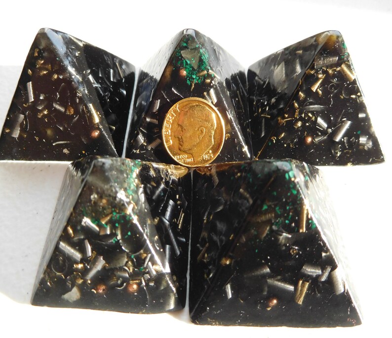 May include: Five black pyramids with gold and green flecks, arranged in a star shape. A US penny is placed in the center of the star.
