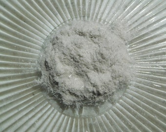 May include: A close-up of a pile of white, fibrous material on a white, textured surface. The material appears to be made of thin, wispy strands.