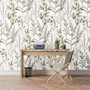 May include: A room featuring a light wood desk, chair, and a vintage typewriter. The wall is adorned with floral wallpaper, showcasing green and grey leaves against a white backdrop. A small potted plant and desk accessories are on the desk.