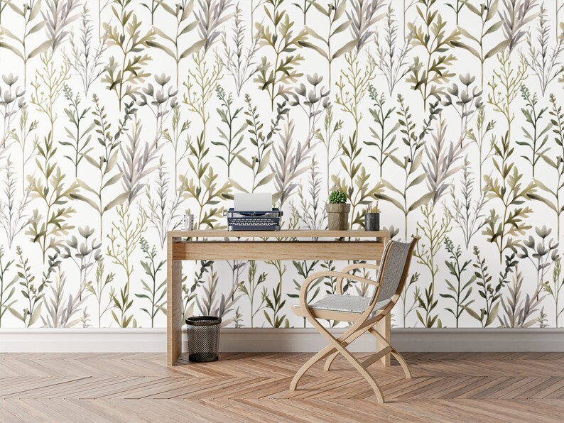 May include: A room featuring a light wood desk, chair, and a vintage typewriter. The wall is adorned with floral wallpaper, showcasing green and grey leaves against a white backdrop. A small potted plant and desk accessories are on the desk.