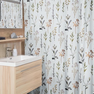 May include: A white shower curtain featuring a repeating pattern of watercolour botanical elements in shades of green, brown, and grey. The bathroom decor includes a wooden vanity and a matching mirror.